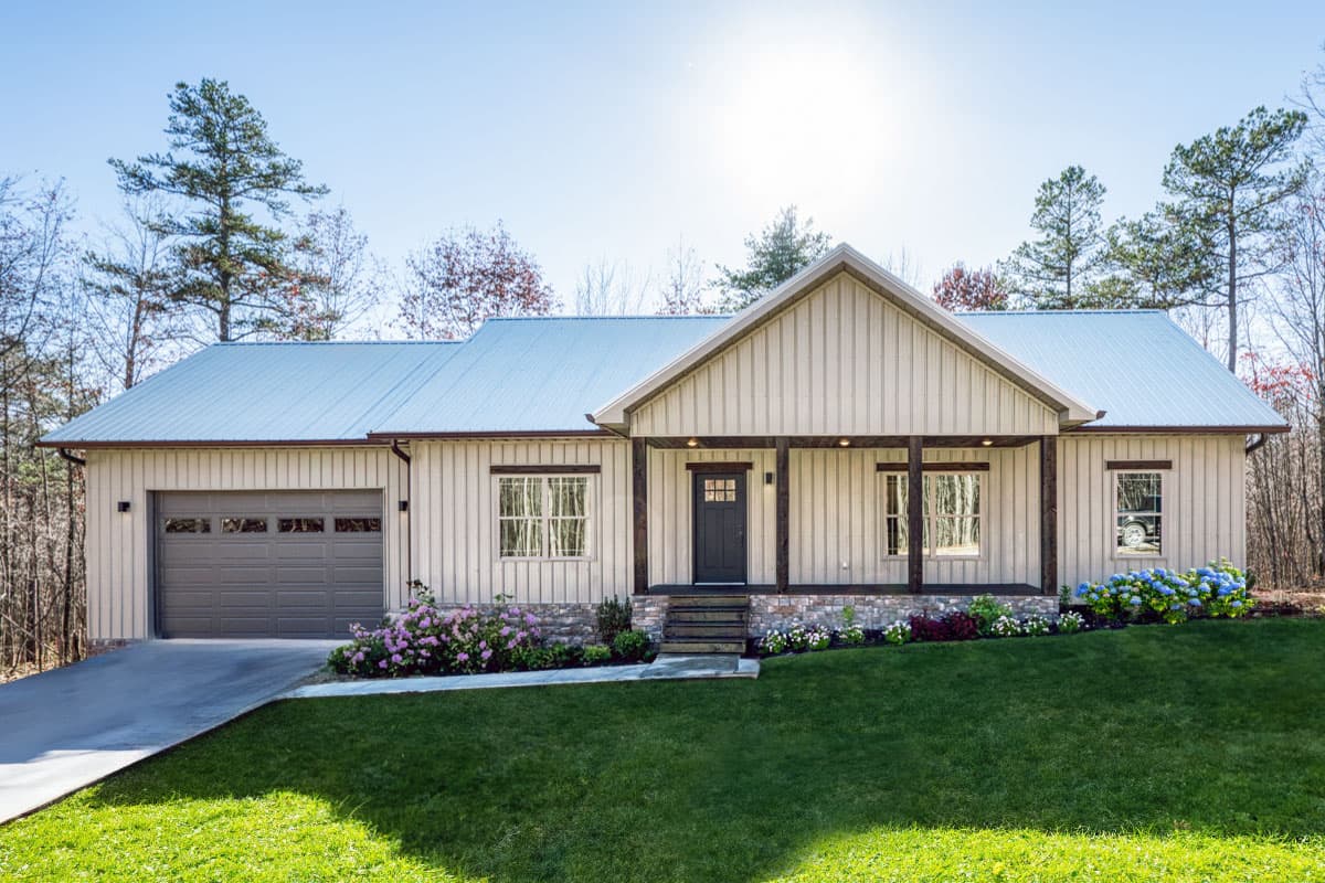 House plan exterior. Ranch style with a gabled porch, metal roof, and attached garage. Exterior features vertical siding and multiple windows.