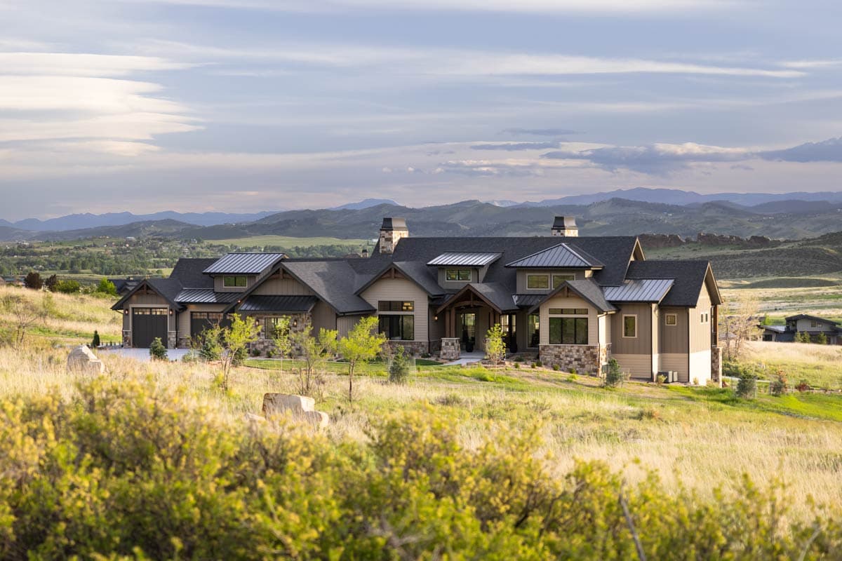 House plan exterior: Modern Ranch style with metal roof, multiple gables, stone accents, and attached three-car garage.