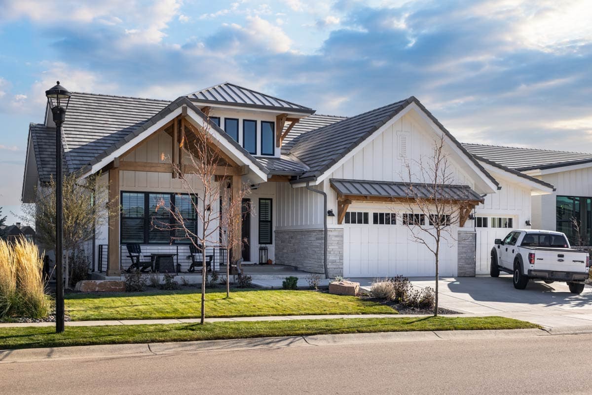 Modern Farmhouse house plan exterior with a prominent gable, exposed wooden beams, stone accents, and a triple-car garage.