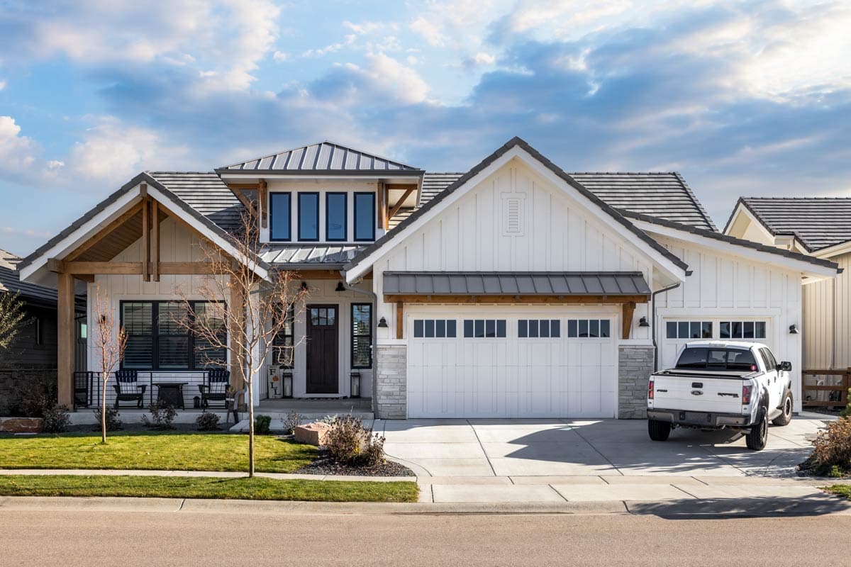 House plan exterior featuring Modern Farmhouse style with two stories, gabled rooflines, a covered porch, and a two-car garage.