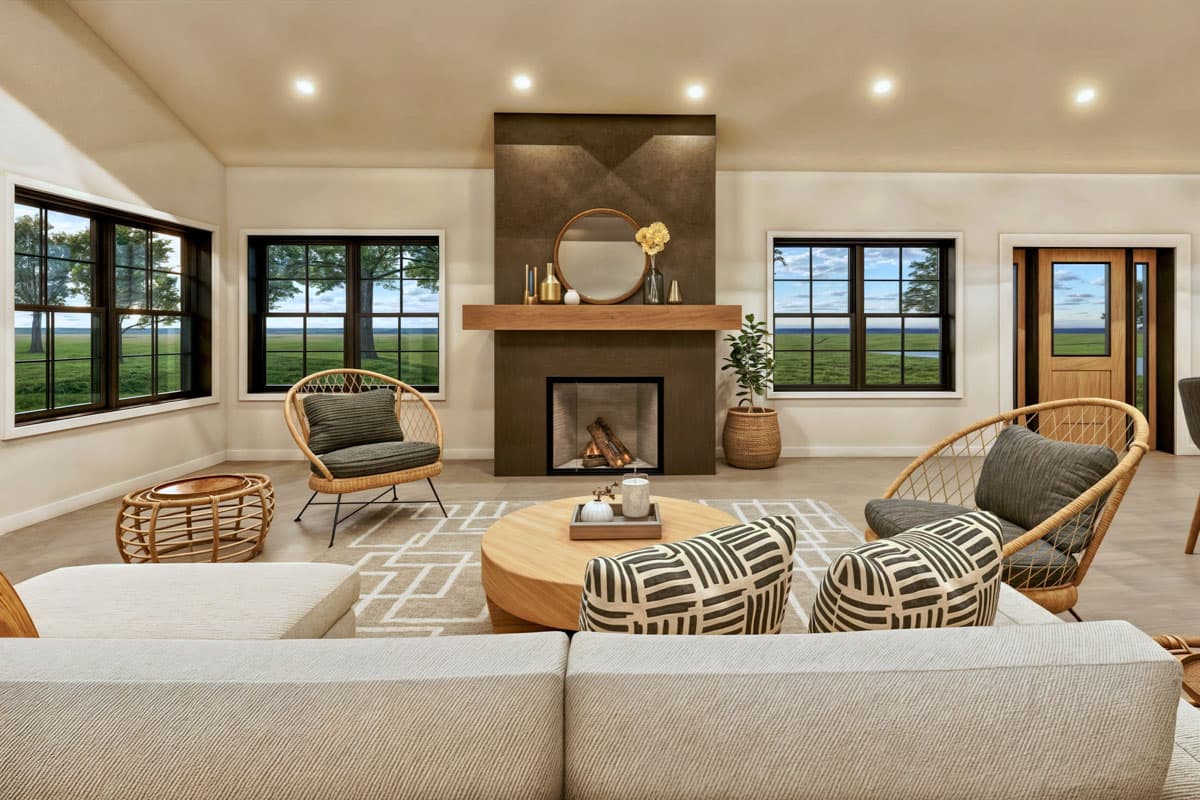 Spacious living room with a fireplace as the focal point, flanked by wicker chairs and large windows overlooking a green landscape.