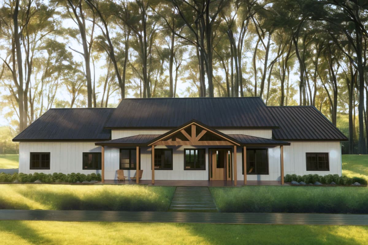 A white farmhouse with a dark roof and a wooden porch. Tall trees are in the background, with a pathway leading up to the house. Two chairs sit on the porch.