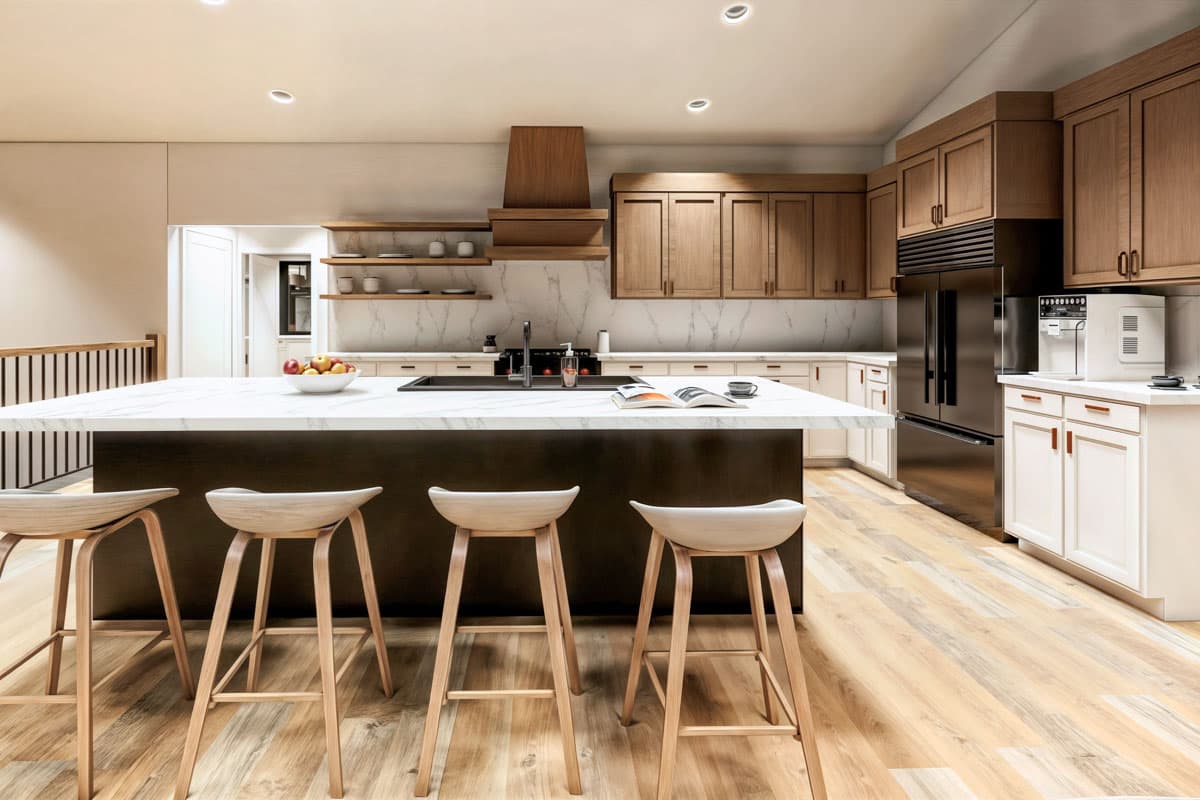 A modern kitchen with a large island with bar stools. Wooden cabinets and a black refrigerator are visible, along with fruit and a book.