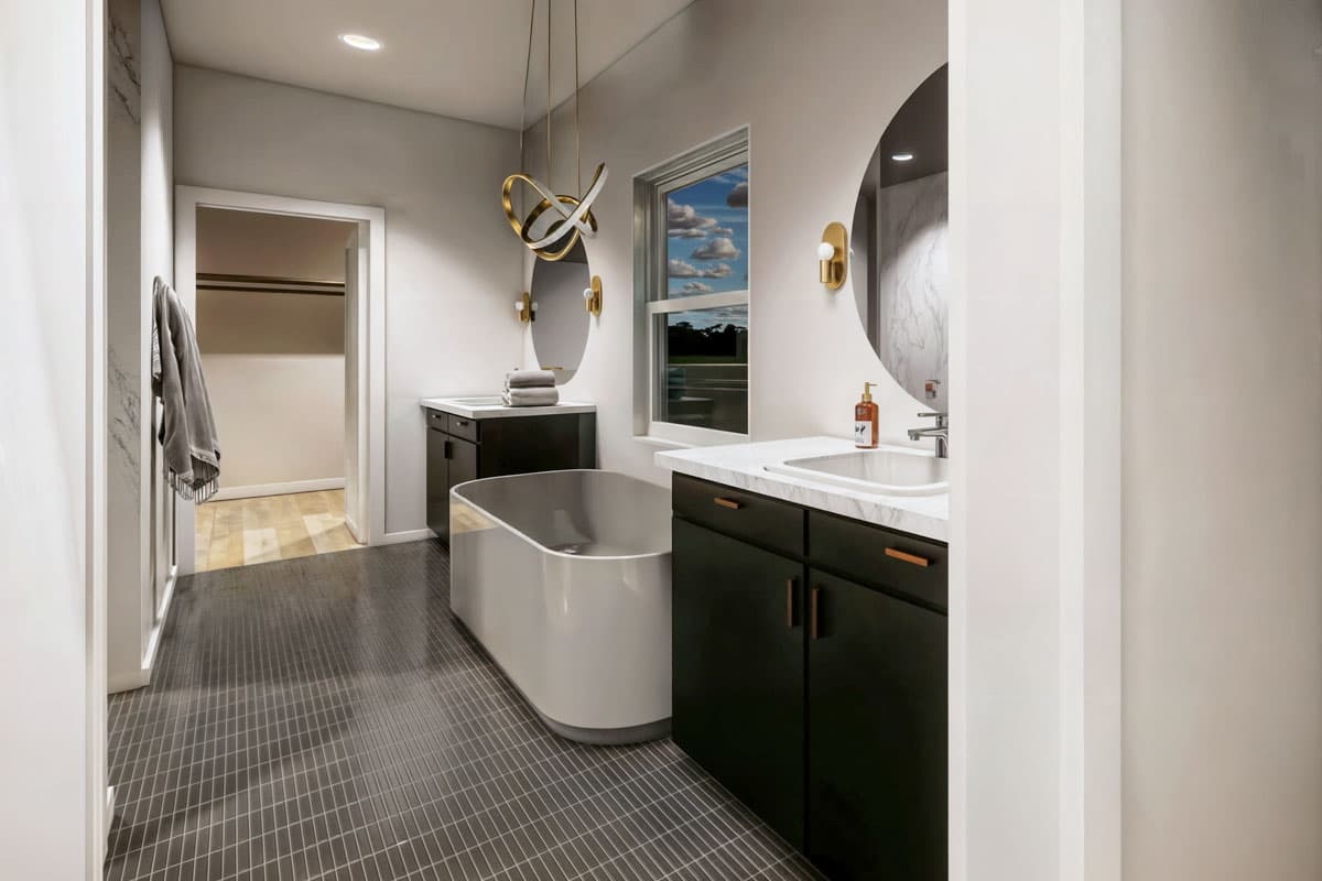 Modern bathroom featuring a standalone tub, dark cabinets, a marble countertop, and a round mirror. A window offers a view of a blue sky.