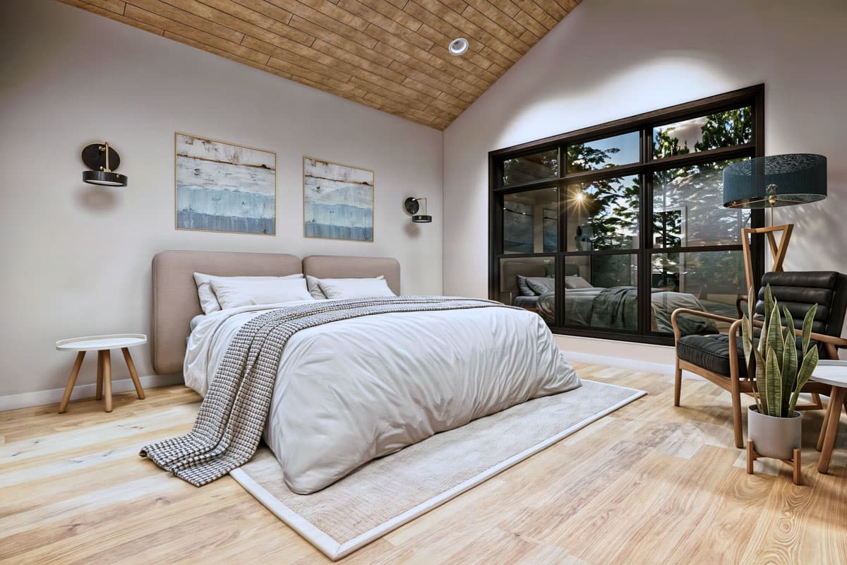 A modern bedroom features a large window with a view of trees, a bed with cream bedding, and minimalist decor. Wood ceiling and floor.