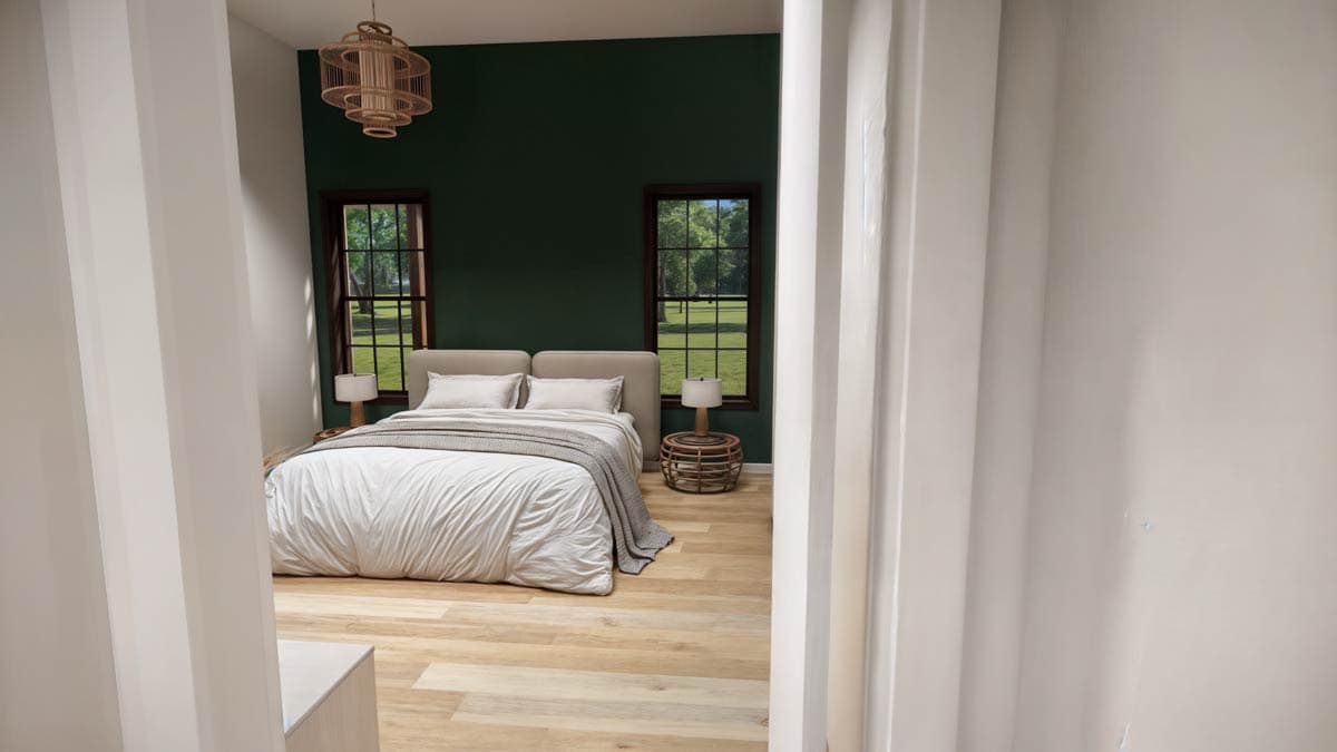 Cozy bedroom with a green accent wall. A bed is centered between two windows overlooking a sunny yard. Natural wood floors and decor enhance the space.