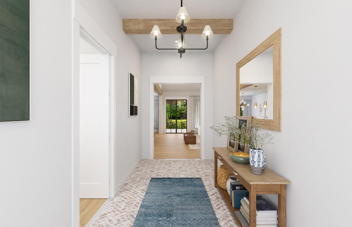 Interior view of a hallway with a wood-beamed ceiling, herringbone tile floor, and console table.