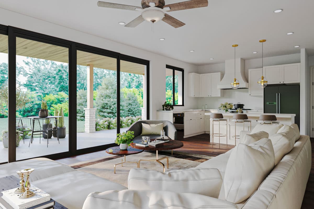 Open-concept living area and kitchen with large sliding glass doors, island, and modern white cabinetry.
