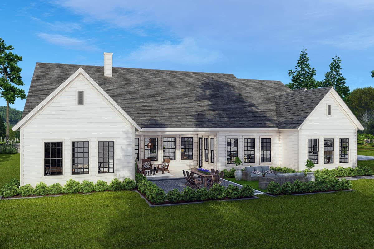 Modern Farmhouse house plan exterior with gables, chimney, and large windows. Features a patio with outdoor dining and seating.