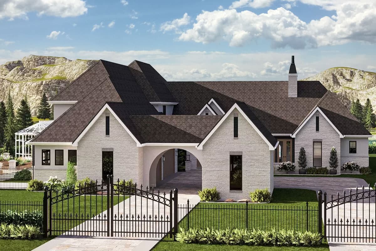 House plan exterior with multi-gabled roof, arched entryway, brick facade, and decorative chimney. Features a black wrought iron fence.