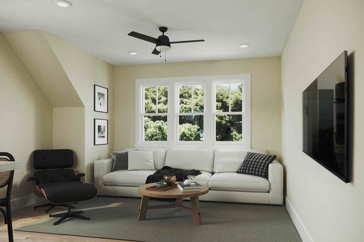 Interior view of a living area with a sectional sofa, coffee table, fan, and large windows.