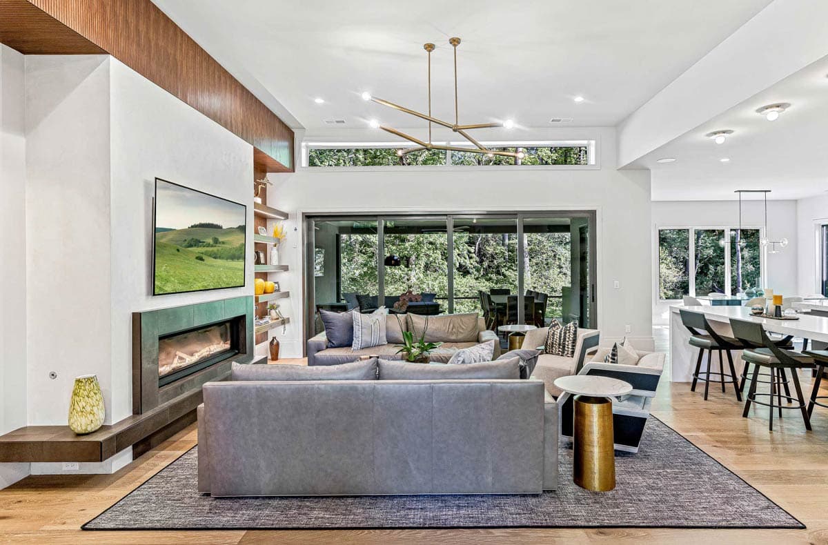 Interior view of a great room with a fireplace, seating area, large sliding glass doors, and a kitchen island.