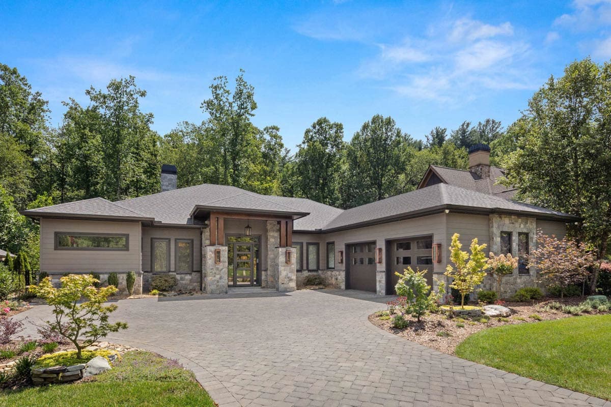 House plan exterior. Modern style, single-story home with stone accents. Features include a covered entry, gabled roof, and attached garage.