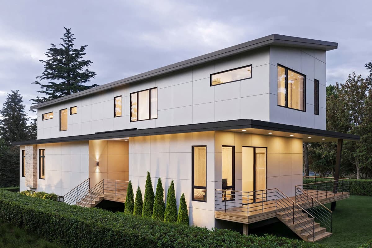 Modern two-story house plan exterior with flat roof, multiple asymmetrical windows, cantilevered balconies, and wood decking.