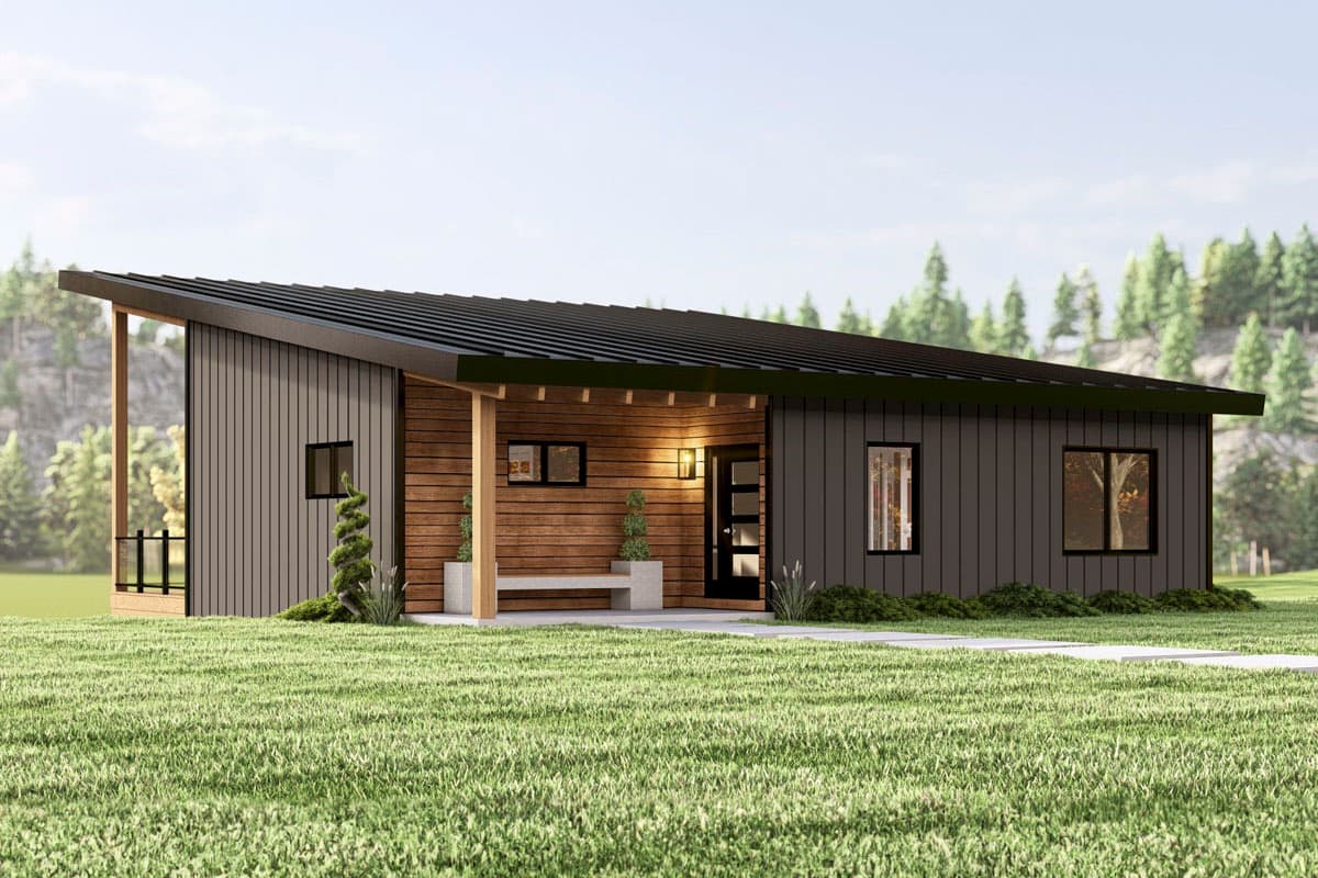 A modern, single-story house with a dark gray exterior, accented by a wooden porch and a sloping black roof, sits on a grassy lawn.