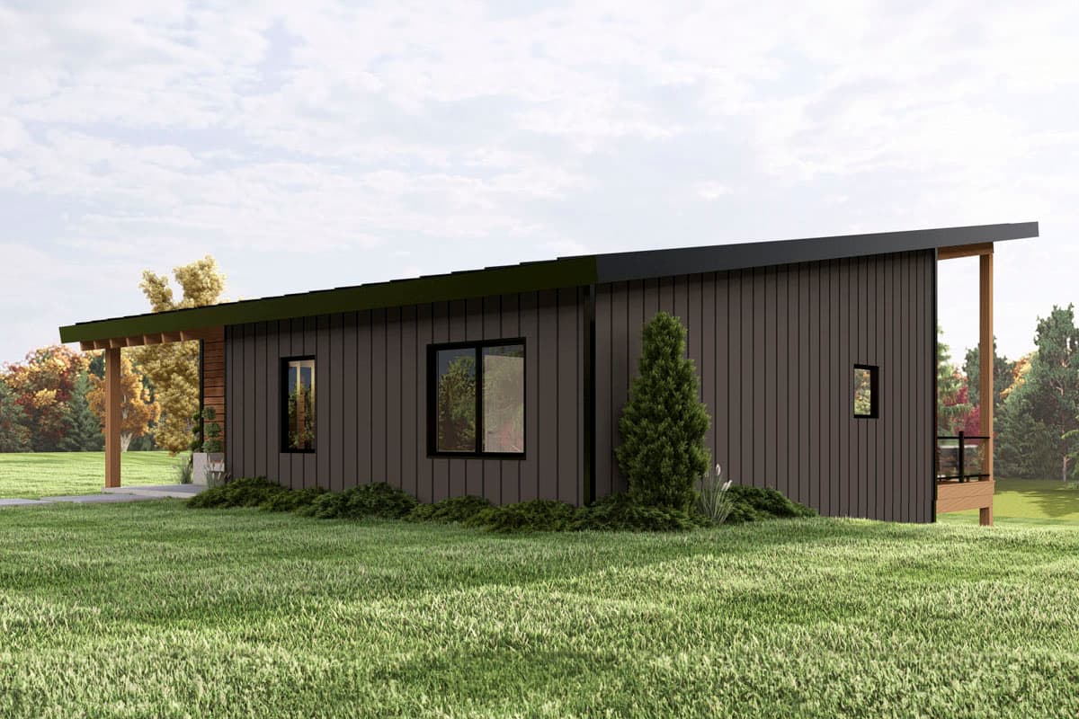 A modern, single-story house with dark brown siding and a black sloped roof, surrounded by a green lawn and trees in the background.