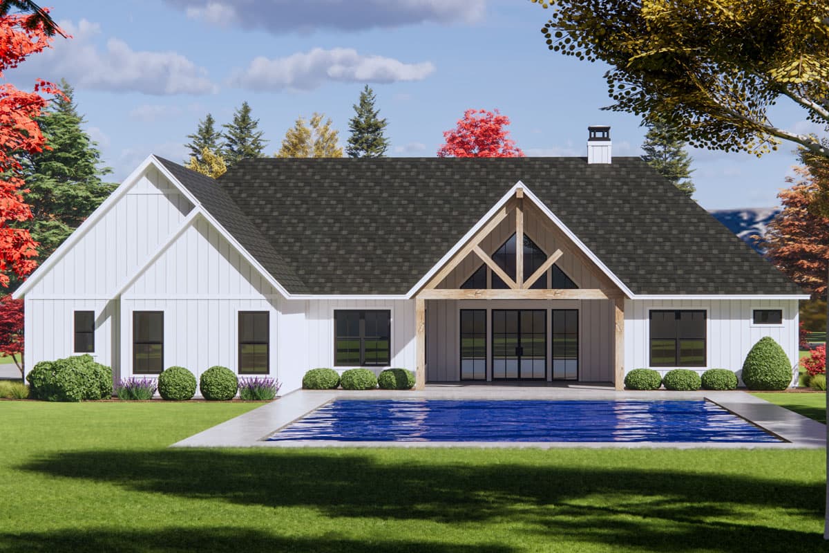 Modern farmhouse exterior, one story, white board and batten siding, gabled roof, prominent wooden beams, and glass doors opening to a pool.