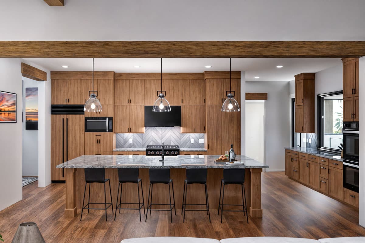 Modern kitchen with wood cabinetry, large island with pendant lights, professional range, and built-in refrigerator.