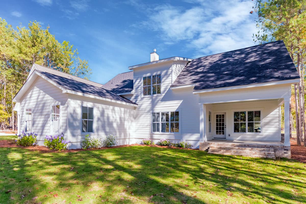 Modern Farmhouse house plan exterior with white siding, gables, dormers, and a covered porch with brick steps.