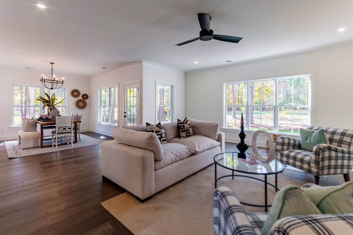 Open concept living and dining areas with large windows, a ceiling fan, and wood flooring.