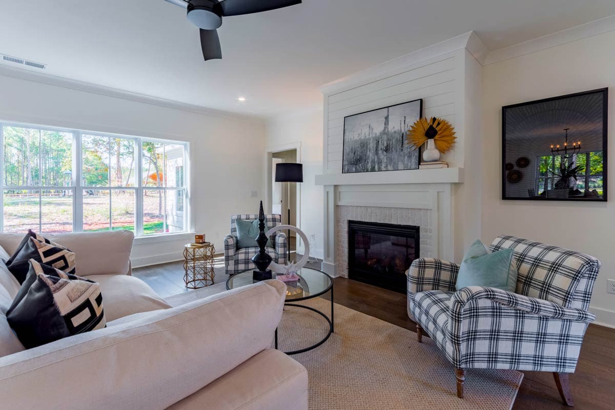 Living room interior with shiplap fireplace, large windows, and plaid accent chairs.