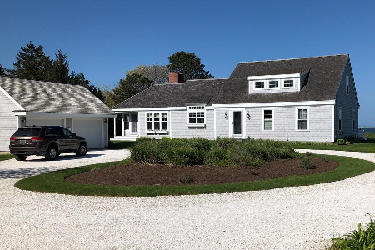 House plan exterior: Shingle-style home with attached garage, dormer, and centered chimney.