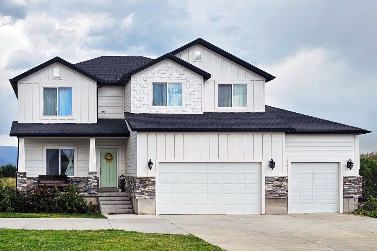 House plan exterior featuring a two-story farmhouse style with a gabled roof, board-and-batten siding, and an attached garage.