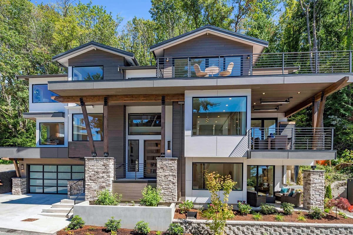 Modern house plan exterior with multiple balconies, a glass garage door, stone pillars, and large windows.