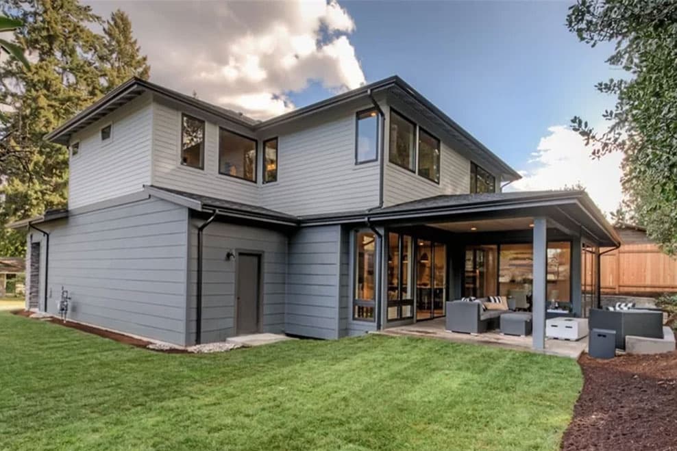 Modern two-story house plan exterior with horizontal siding, multiple gables, large windows, and covered patio.