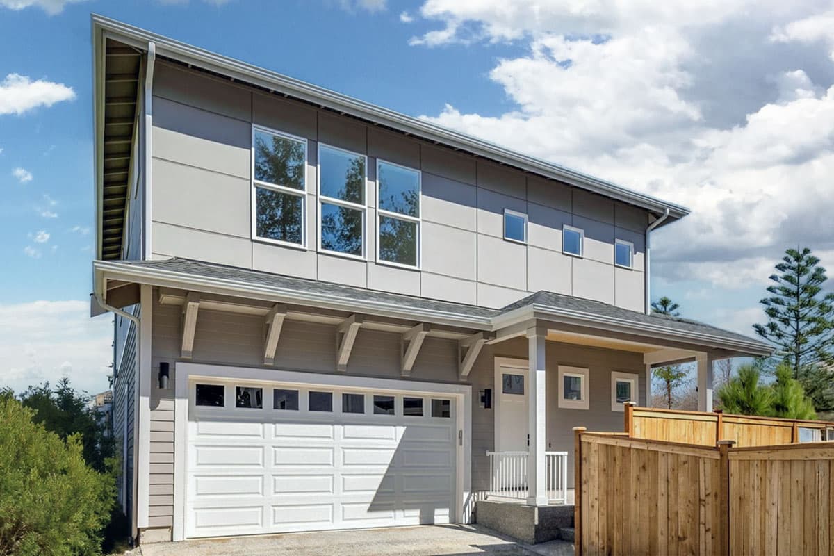 House plan exterior. Two-story Modern house with a gable roof, covered porch, and a two-car garage. Features include large windows and brackets.