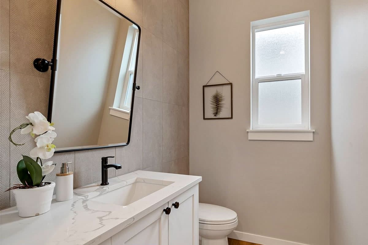 Powder room with a white vanity, quartz countertop, black faucet, square sink, and tiled accent wall.