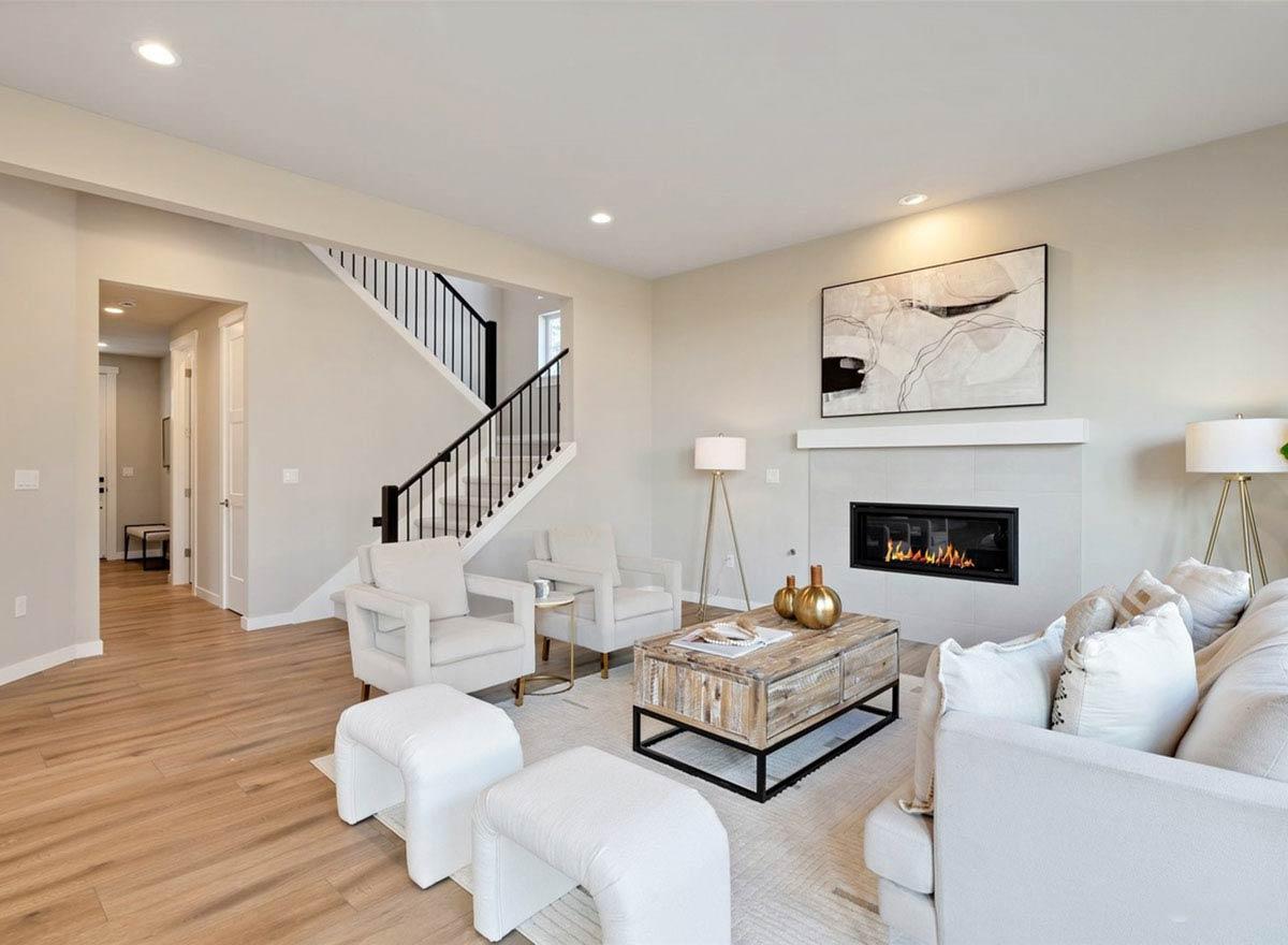Contemporary living room with fireplace, minimalist art, and staircase with black railing.