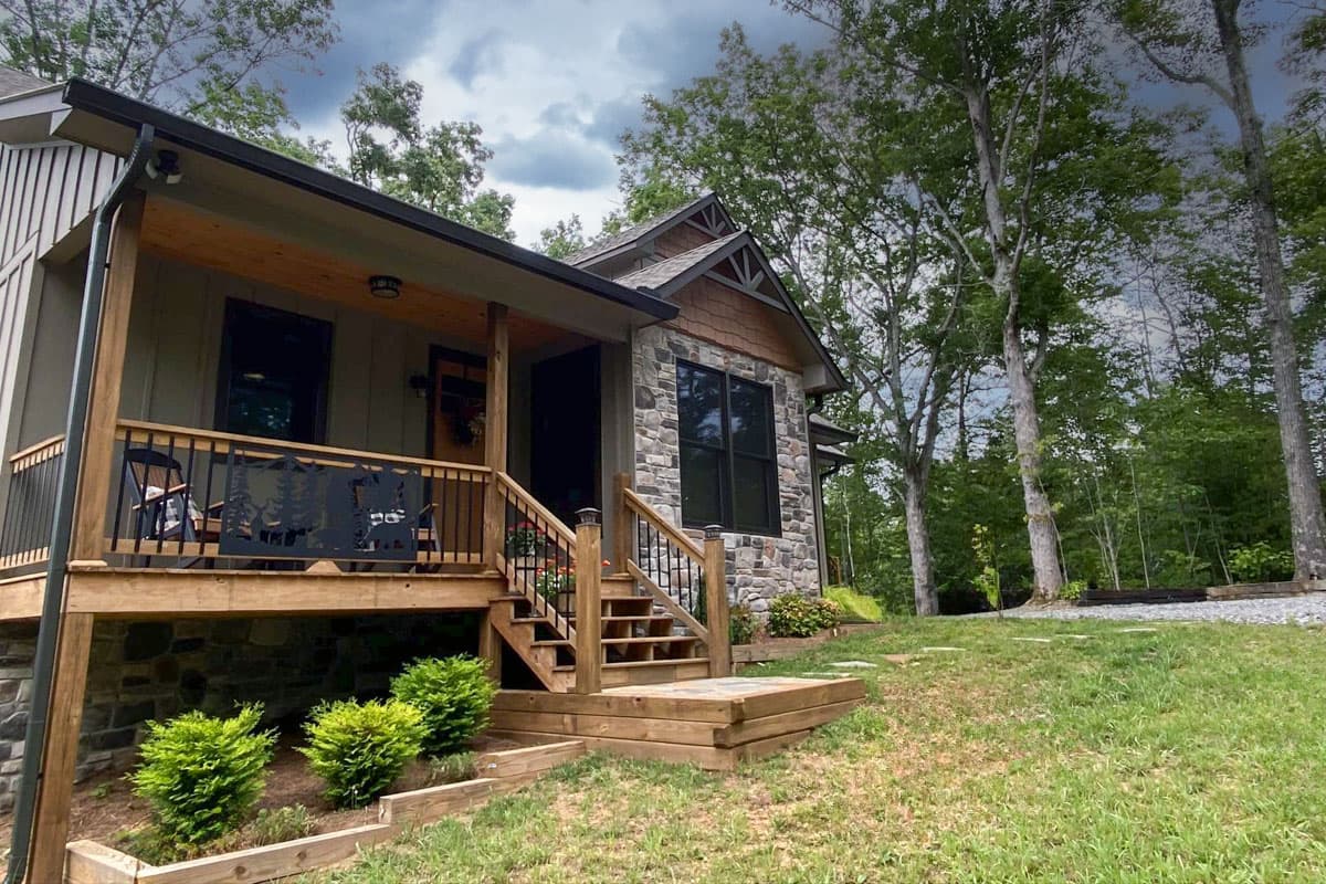 House plan exterior: one-story home with a covered porch, stone facade, and prominent gables.
