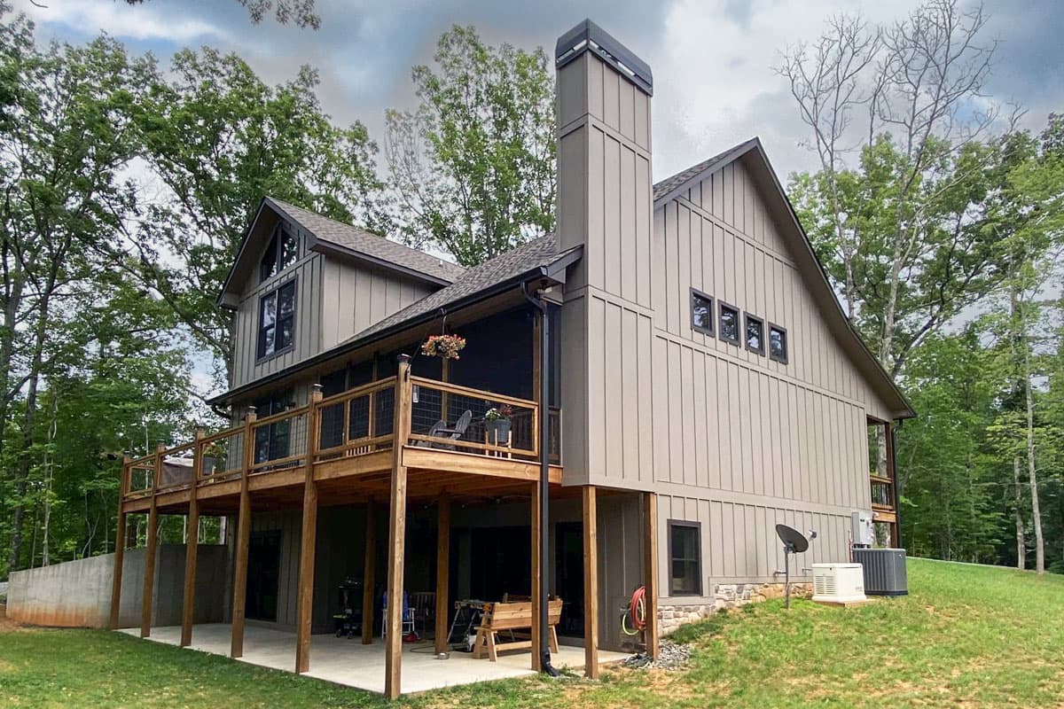 House plan exterior, modern style, two stories, with a large wrap-around deck and prominent vertical siding.