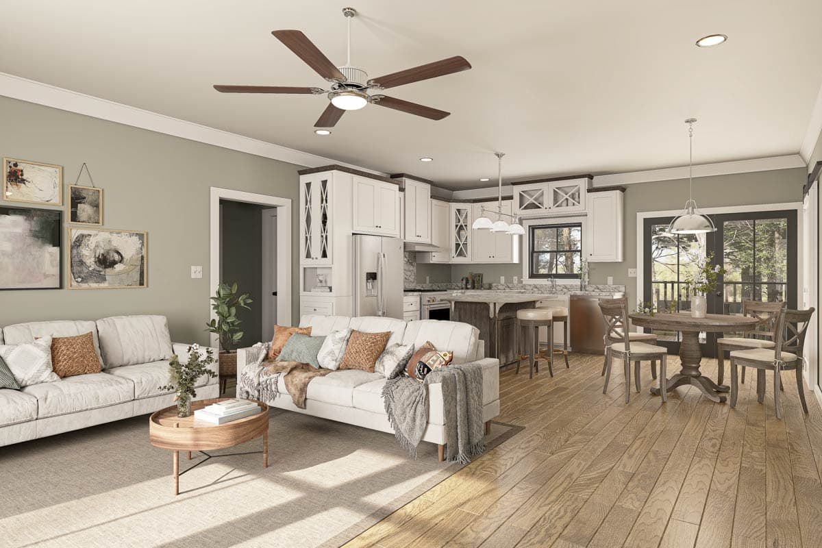 Open concept living area with white sofas, kitchen island with seating, and adjacent dining area. Features a ceiling fan.