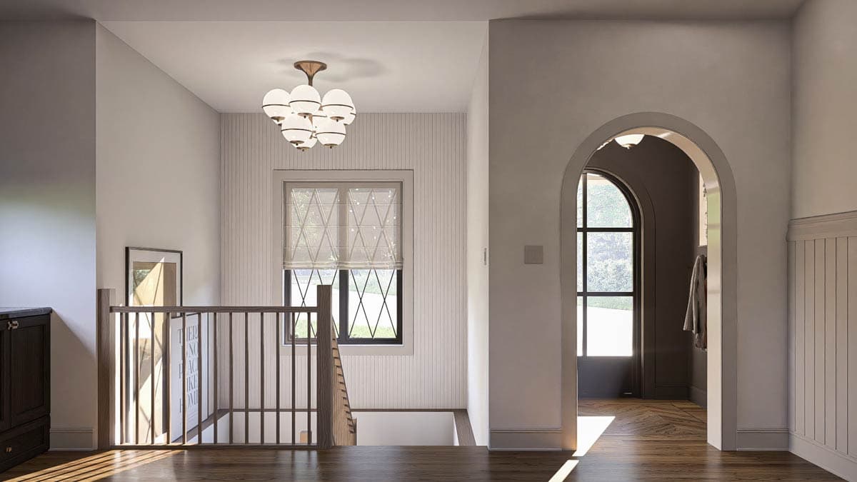 Interior view of a hallway with a staircase, arched doorway, and patterned window. Features include a globe chandelier and dark wood flooring.