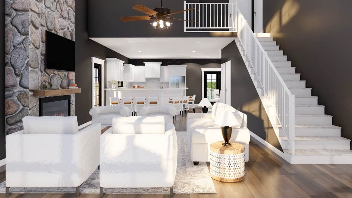 Great room with stone fireplace, kitchen island, and open staircase leading to loft.