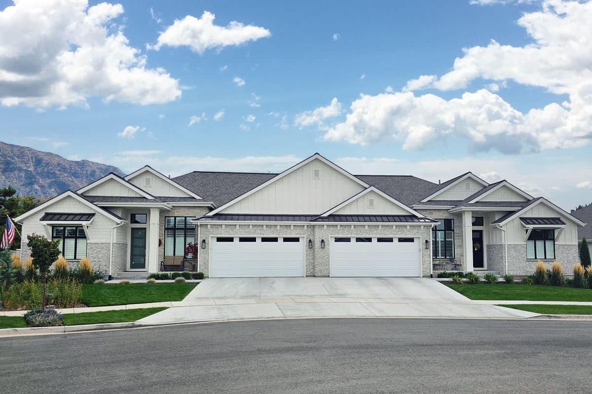 House plan exterior. Modern Farmhouse style with two stories. Features include gabled rooflines, two garage doors, and front porch with awnings.