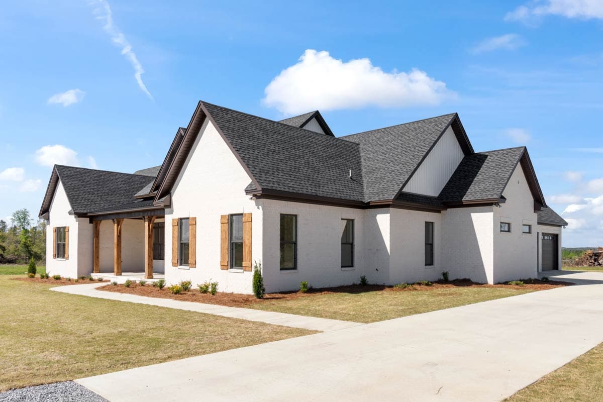 House plan exterior with white brick, dark gables, prominent dormers, wood-shuttered windows, and covered entry porch.