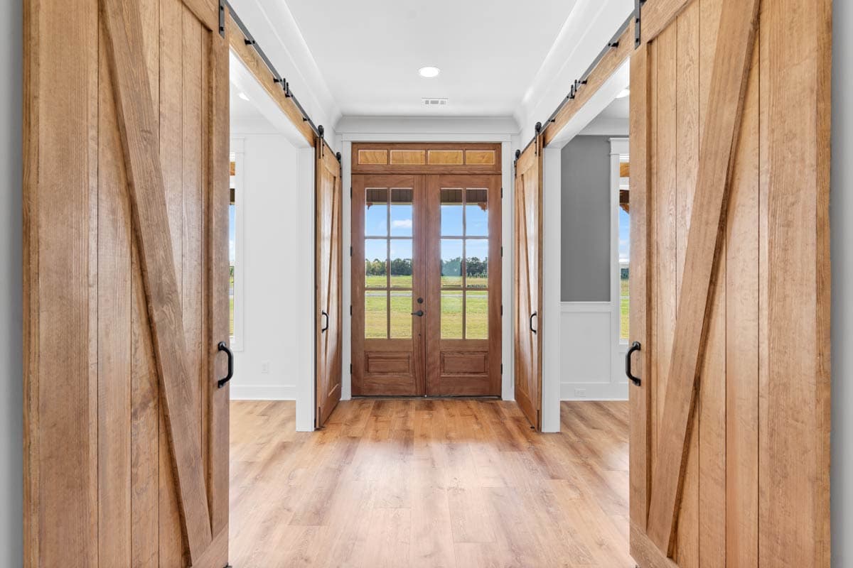 Interior view of foyer with double barn doors, double entry doors with glass panes, and wood flooring.