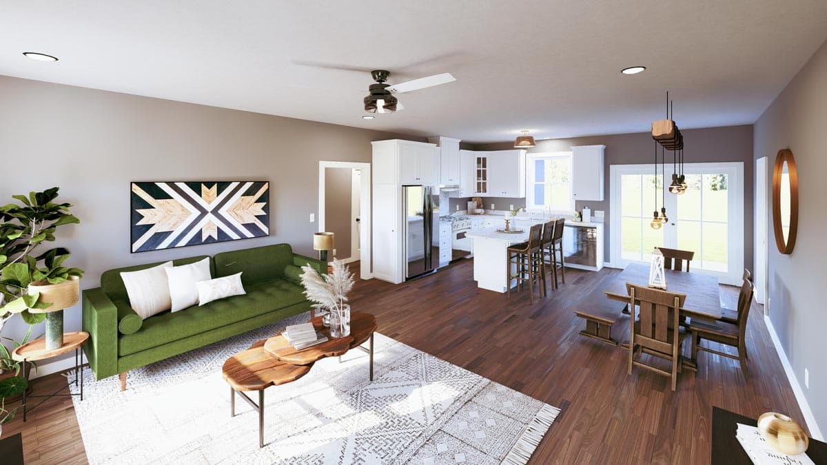 Open concept living space with green sofa, kitchen island with bar stools, and dining area.