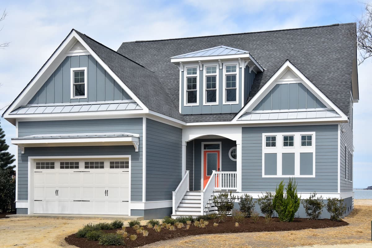 House plan exterior: Modern Farmhouse style, two stories, gable dormer, attached garage, covered entryway with red door.
