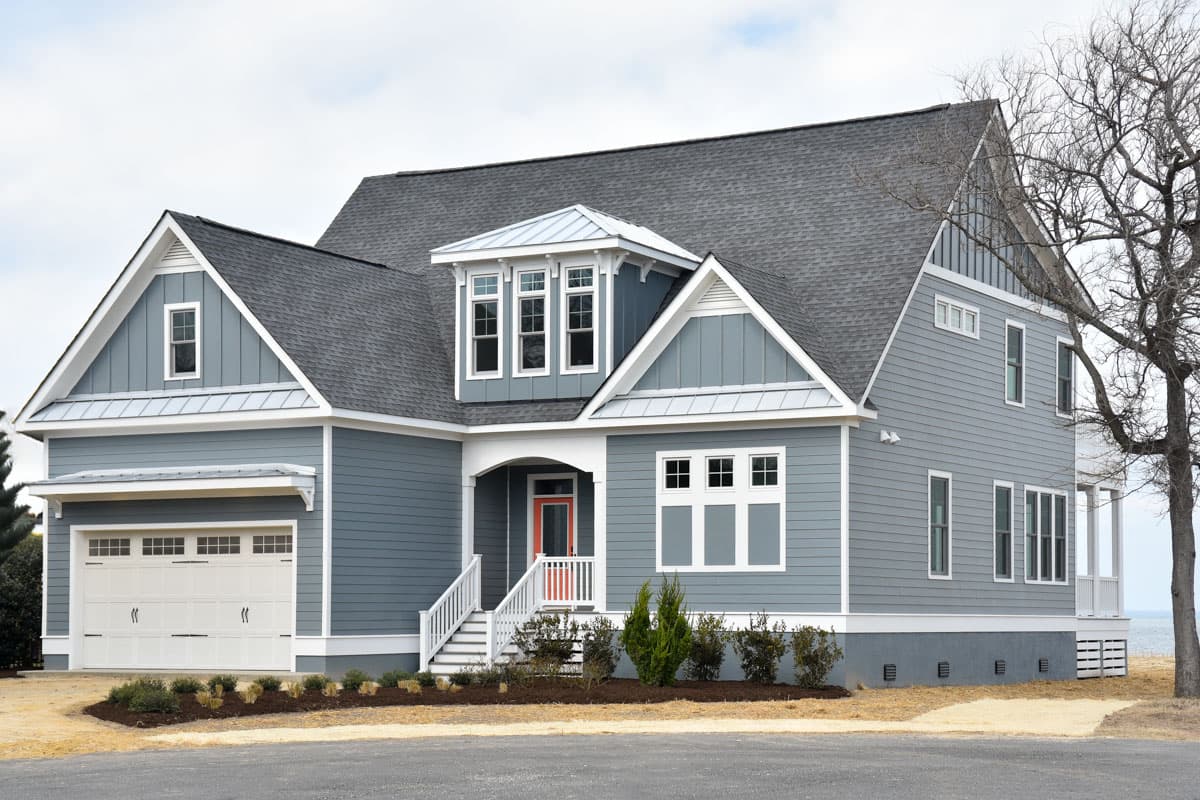 House plan exterior: Modern Farmhouse style, 1.5 stories, with a front-facing garage, dormers, and a covered entry.