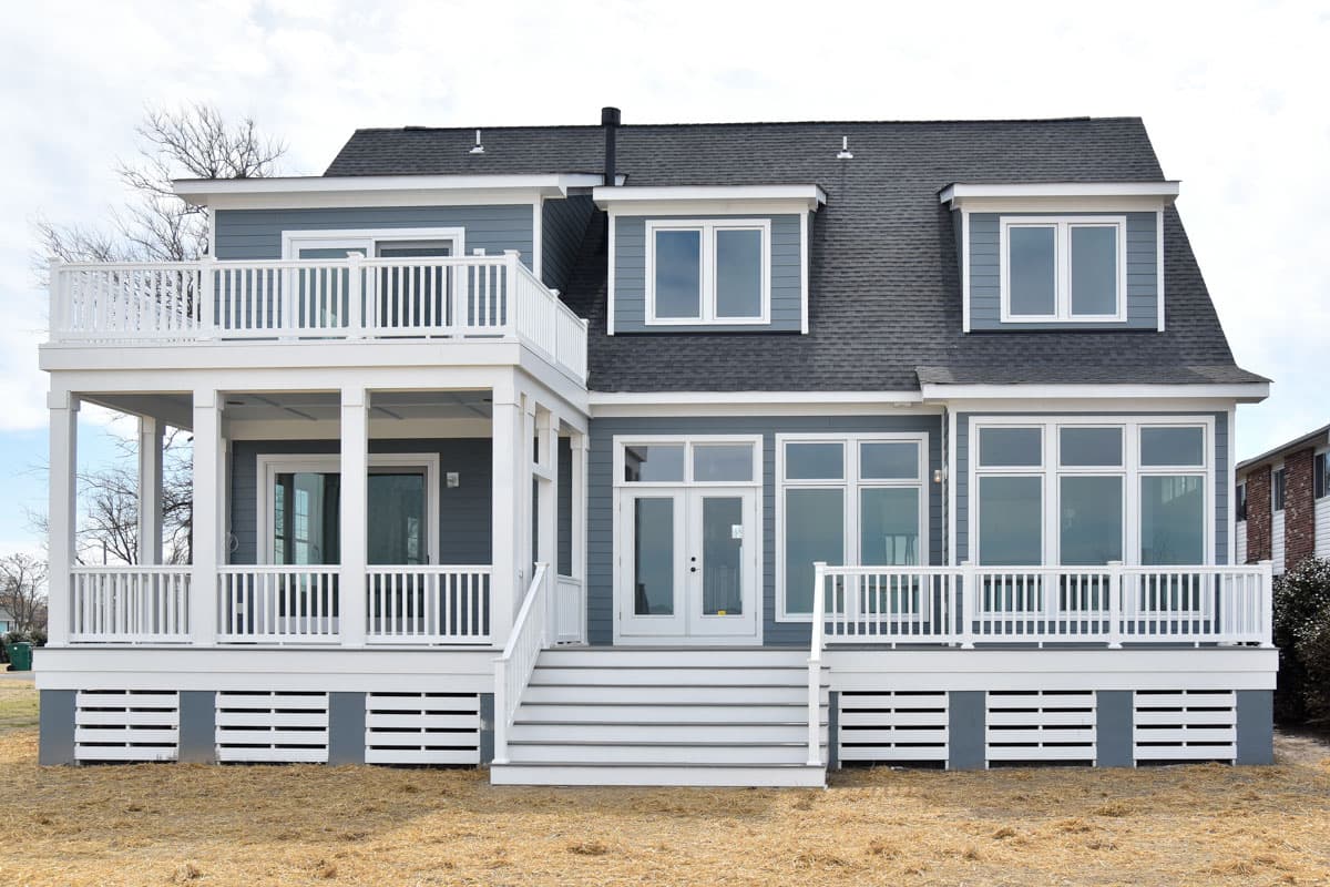 House plan exterior with two stories, gabled dormers, multiple balconies, and a prominent front entry stair.