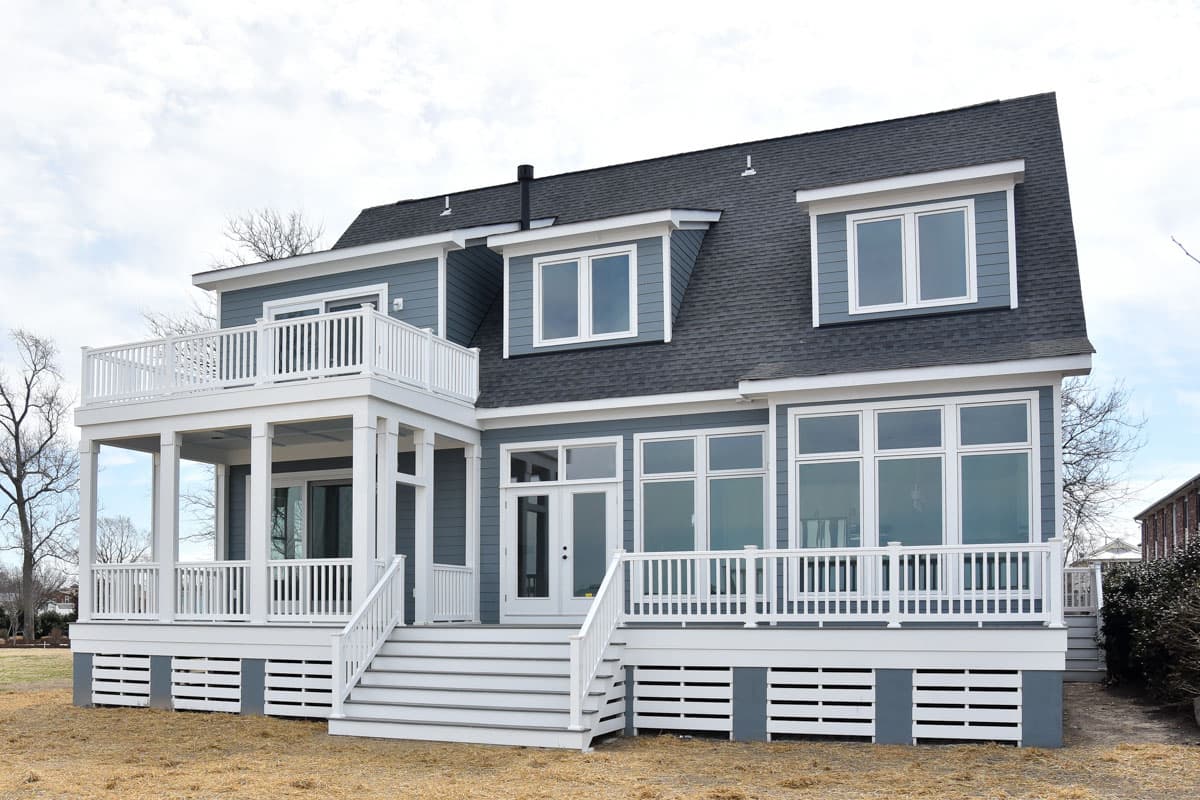 House plan exterior of a two-story home featuring a large wrap-around porch, second-story balcony, and dormer windows.