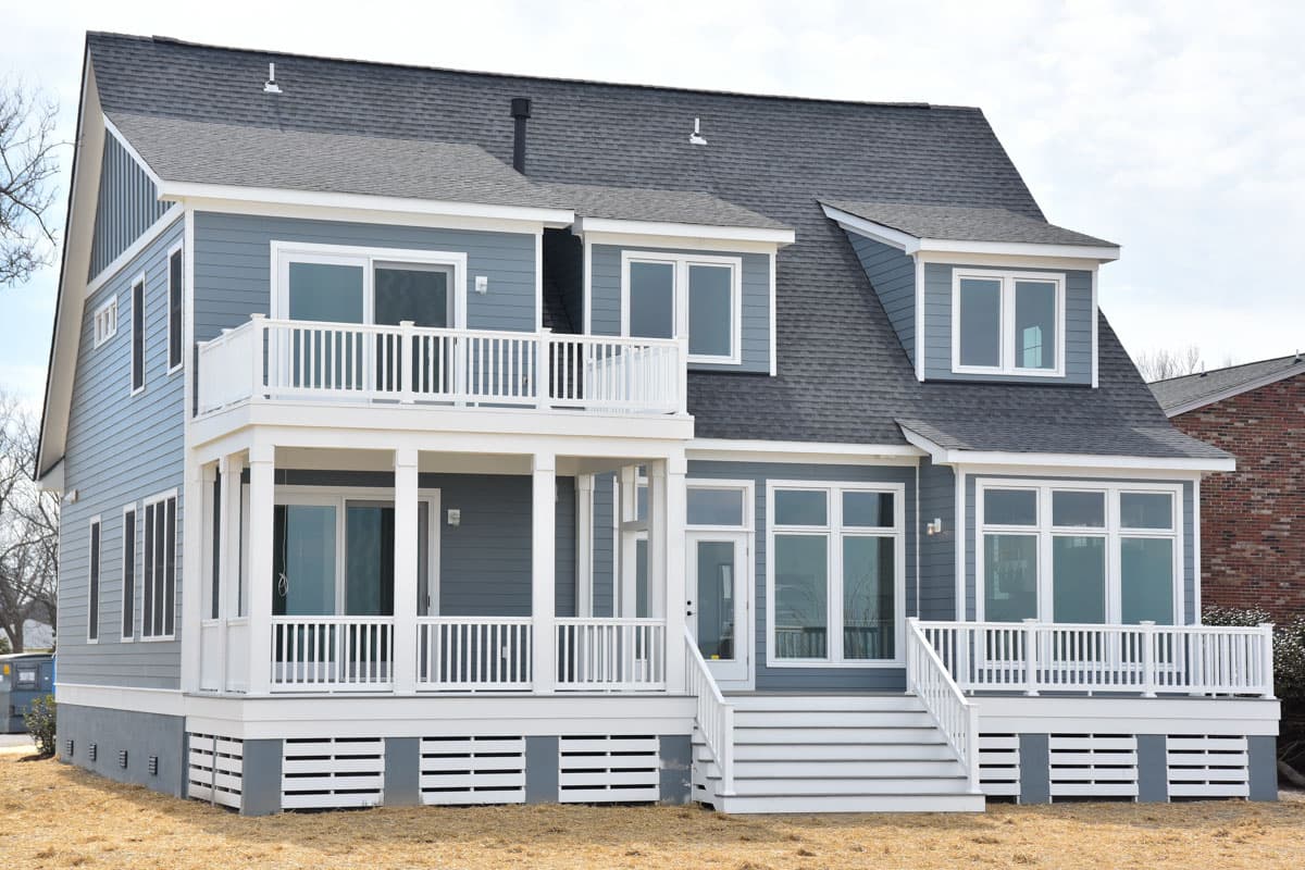 House plan exterior of a two-story coastal home with gabled dormers, covered porch, and upper-level balcony.