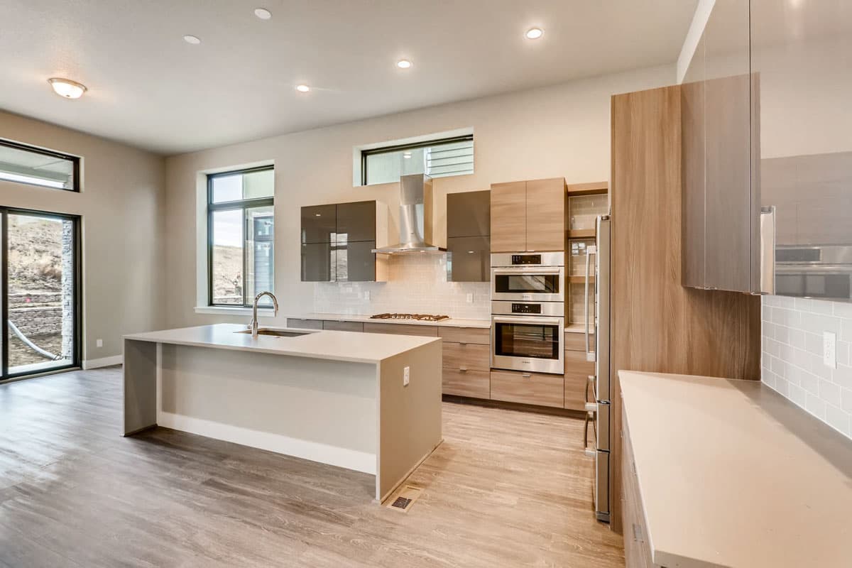 Contemporary kitchen with large island, stainless steel appliances, dual ovens, and extensive cabinetry.