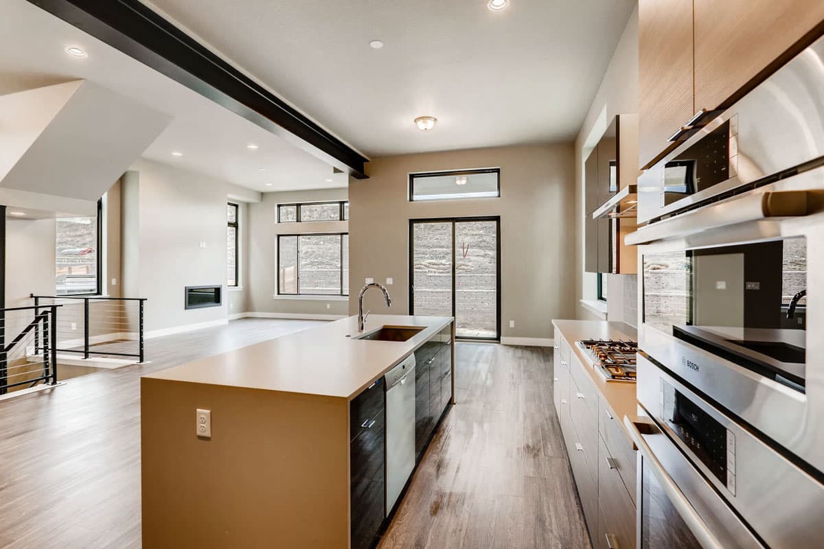 Modern kitchen with island, stainless steel appliances, and open layout to living area with fireplace.