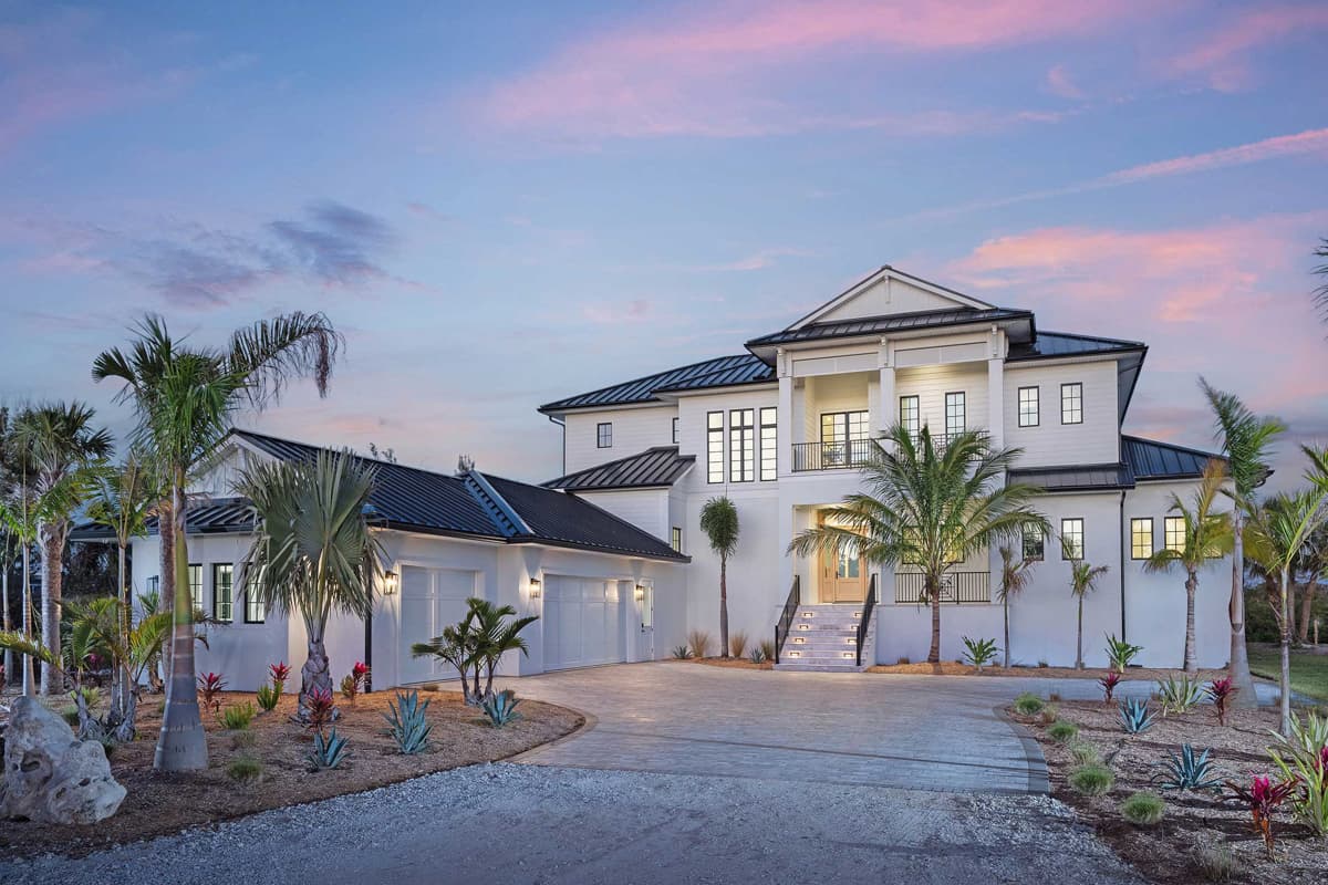 House plan exterior with two stories. Features include a front porch with columns, a two-car garage, and a combination of gabled and flat rooflines.