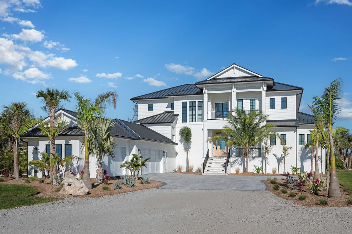 House plan exterior: Two-story modern home with metal roof, upper balcony, and attached three-car garage.